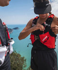 Person wearing Pace Running Vest Hydration Pack With 2 UltraFlasks 8L Trail Backpack For Men And Women Red Medium on a scenic trail.