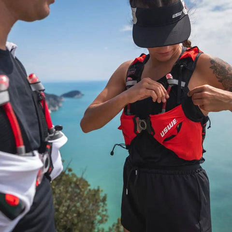 Person wearing Pace Running Vest Hydration Pack With 2 UltraFlasks 8L Trail Backpack For Men And Women Red Medium on a scenic trail.