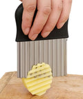 HTBMALL crinkle cutter held in hand with black handle and ribbed stainless blade slicing potato on a board