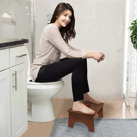 Woman using Wooden Toilet Stool For Kids And Adults, Anti Slip Bamboo Potty Training Step Stool, 7 Inch Rise, in bathroom setup.