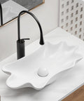 HAOCHRYSYPH Ceramic Shell Vessel Sink Bowl, Milk White, 24.41x13x4.73 in. above-counter bowl with modern black faucet.