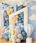 Balloon arch with dusty slate, fog blue, and sand balloons. Features hot air balloon and cloud foil balloons, number 1 in front.