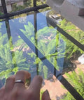 Hand placing Aluminum L Shaped Wall Corner Guard Peel And Stick Edge Protector on window edge, reflection of trees
