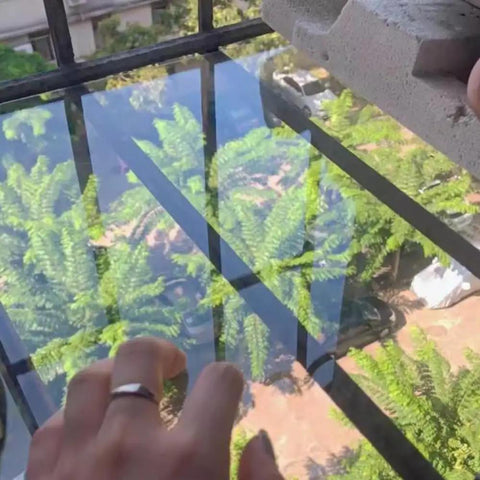 Hand placing Aluminum L Shaped Wall Corner Guard Peel And Stick Edge Protector on window edge, reflection of trees