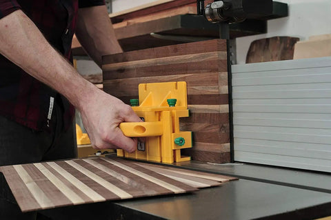 Person using GRR RIPPER GR 100 3D Adjustable Table Saw Pushblock 2 Pack Delivers Pro Grade Precision And Kickback Control With A Rock Solid Grip Keeping Your Hands Safe While You Push Through Lumber For Smooth Accurate Cuts Every Time In Bright Yellow on striped wooden board