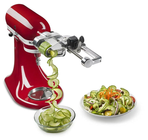7 Blade Spiralizer Plus with Peel Core and Slice Attachment for stand mixer in red, spiralizing cucumber into a bowl.