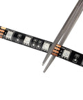 Close-up of Waterproof 16.4ft RGB LED Strip Lights 5050 Color Changing Rope Lights For Bedroom Decor being cut with scissors.