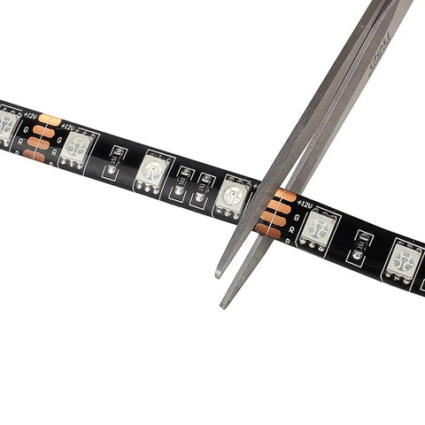 Close-up of Waterproof 16.4ft RGB LED Strip Lights 5050 Color Changing Rope Lights For Bedroom Decor being cut with scissors.