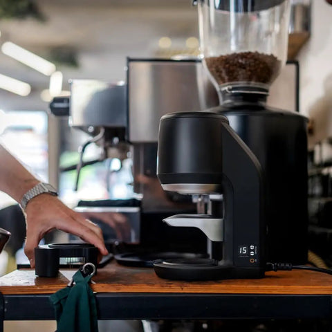Electric Auto Leveling Espresso Tamper For 57.3 Mm Portafilters in a modern cafe setting with a sleek design.
