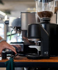 Electric Automatic Espresso Tamper For Home Baristas Featuring Self Leveling Precision With A Tight 53mm Fit providing consistent pucks on a wooden counter.