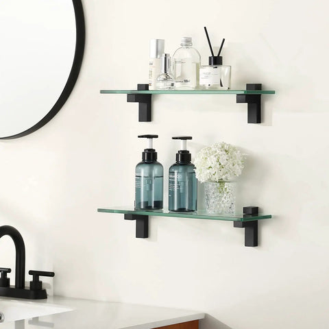 Two Pack 16 Inch Tempered Glass Bathroom Shelves With Matte Black Wall Mount Floating Shelves For Vanity Or Shower Sturdy Modern Storage Easy Install Space Saving Design For Quick Organization showcasing toiletries on bathroom wall.