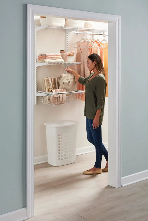 Woman organizing clothes in closet with white sliding basket for closet organization, sturdy pull out wire drawer for storage.