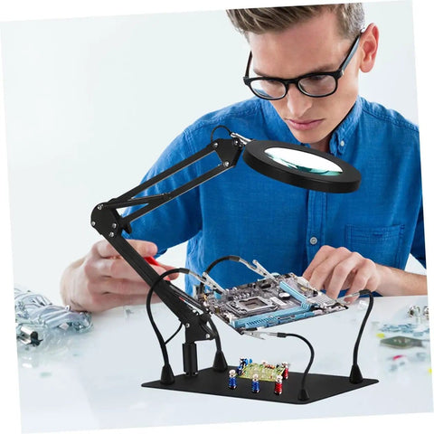 Adjustable Soldering Workbench Clips Set With Iron Alligator Clamps For Electronics Repair Totally Handy Third Hand Fixture Lamp Clamps And Magnifying Glasses For Precision DIY Projects in use by a person working on a circuit board.