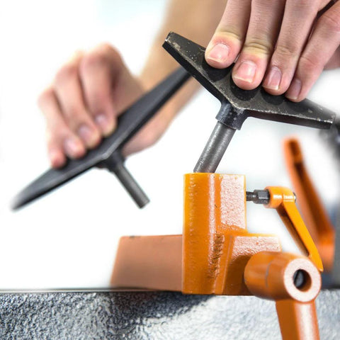 Mini benchtop wood lathe with orange base; close-up of tool rest and hands adjusting the clamp