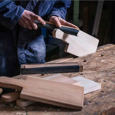 Person using Auto Body Sanding Kit With 28 Pcs Wet Dry Sandpaper Pack on wooden boards, showing sanding process.