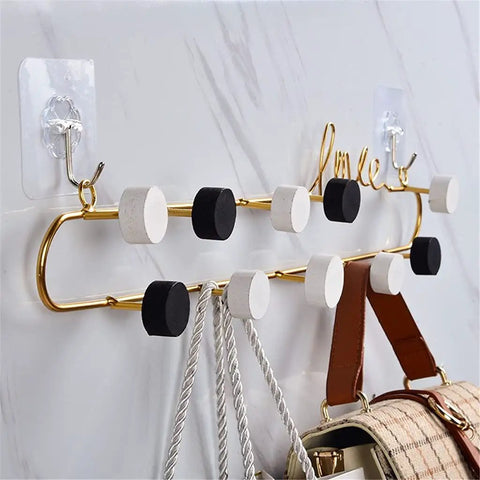 Top Tier Wrought Iron Letter Wall Hooks Slick Gold Finish Heavy Duty Coat And Key Hangers Modern Entryway Decor displayed with hooks and bags.