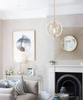 Living room with gold pendant light fixture and elegant white flower chandelier over a cozy space.