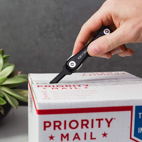 Hand using Finger Friendly Key Shaped Box Opener for Easy Package Opening on the Go Clips On Your Keychain or Inside Your Pocket
