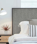 Charcoal Gray Twig Hygge Herringbone Peel And Stick Wallpaper applied on headboard in cozy bedroom.