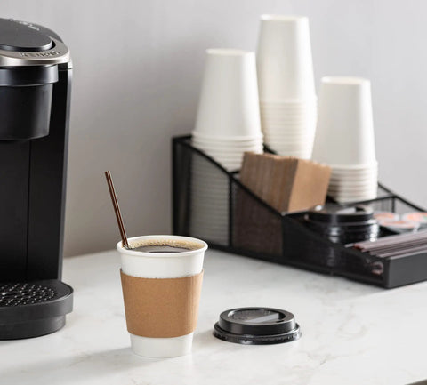 12 Oz Disposable Coffee Cups With Lids And Heat Resistant Sleeves, 100 Sets For Grab And Go Coffee next to coffee maker