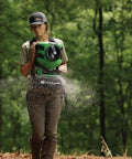 Person using Manual Seed Spreader With 35 Pound Hopper For Food Plots And Land Management Detachable Harness 10 To 20 Foot Throw Radius