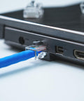 Close-up of Cat6 RJ45 Connectors 110 Pack For Ethernet Cables With Gold Plated 8P8C Pins plugged into a laptop port