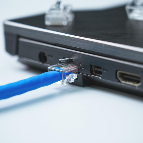 Close-up of Cat6 RJ45 Connectors 110 Pack For Ethernet Cables With Gold Plated 8P8C Pins plugged into a laptop port