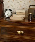 Close-up of a wooden dresser with brass hardware featuring the Six Piece Set Of Antique Brass Cabinet Knobs With Industrial Backplates