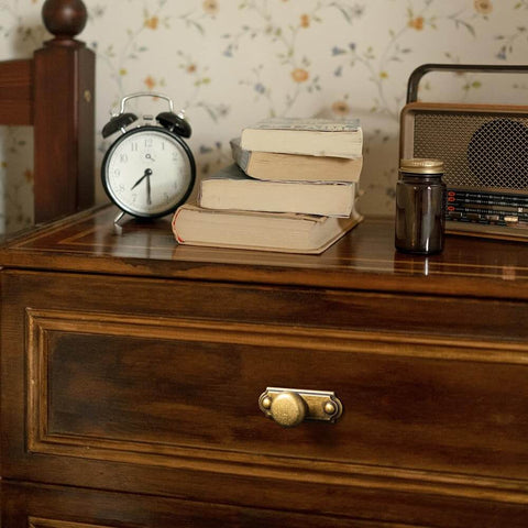 Close-up of a wooden dresser with brass hardware featuring the Six Piece Set Of Antique Brass Cabinet Knobs With Industrial Backplates