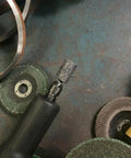 Close-up of an electric rotary tool with a cylindrical grinding stone attached, part of a Ten Piece Set Of Sixteen Millimeter Aluminum Oxide Mounted Grinding Stones For Electric Rotary Tools With One Quarter Inch Shank Cylindrical Grinding Bits For Metal Wood Plastic Deburring And Shaping Durable And Wear Resistant.