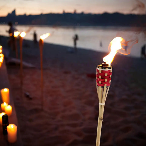 Two Pack Bamboo Tiki Torch Oil Lamp Set For Garden And Patio Outdoor Lighting with Citronella Scented Fuel on beach at sunset