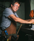 Man using a saw wearing Heavy Duty Canvas Tool Bag For Men With 16 Pockets, Padded Adjustable Shoulder Straps, Brown.