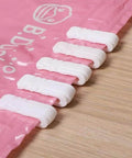 10 Pack Vacuum Bag Clips With Sliding Grip For Tight Seals shown securing a pink storage bag on a wooden surface.