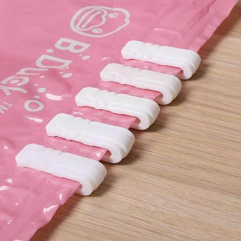 10 Pack Vacuum Bag Clips With Sliding Grip For Tight Seals shown securing a pink storage bag on a wooden surface.