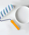 Two Piece Seamless Corner Paint Roller With Dual Grip Handles For Conquering Wall Edges And Tight Corners Lint Free Rolling Design on a white background next to a paint container.