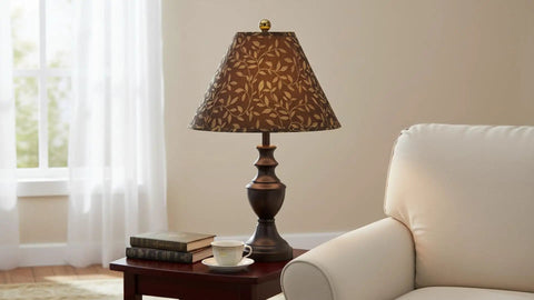 A decorative table lamp with a patterned brown shade on a side table next to a couch in a cozy living room setting.