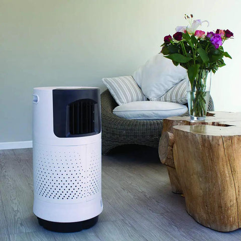 Portable Evaporative Air Cooler For Bedroom And Office Electric Standing Cooling Fan in white beside a wooden table and flowers.