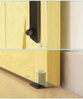 Close-up of 66 Inch Bi Folding Sliding Barn Door Hardware Kit installed on yellow wood, showing roller and black floor guide with measurements.