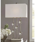 Jaala Modern Glam Metal And Crystal Table Lamp In Silver 31.75 Inch Tall With Crystal Accents next to white flowers on table