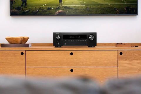 Front view of 7.2 Channel AV Receiver With Built-In HEOS And 8K HDMI Dope Wireless Streaming Dolby Atmos HDR10 Plus Dynamic HDR DTS X WiFi And Bluetooth Plug And Play Setup For Small To Medium Rooms And Smart Home Vibes on wooden cabinet