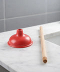 Eighteen Inch Heavy Duty Toilet Plunger Featuring A Thick Red Rubber Cup And Sturdy Wood Grip ready on marble countertop.