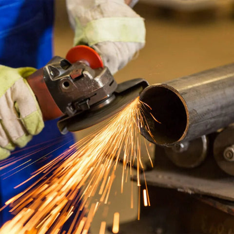 Side view of angle grinder with orange guard grinding a metal pipe, sparks flying.