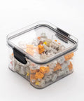 Front view of a square transparent plastic keyboard switch storage box with a black latch, filled with white and orange switches.