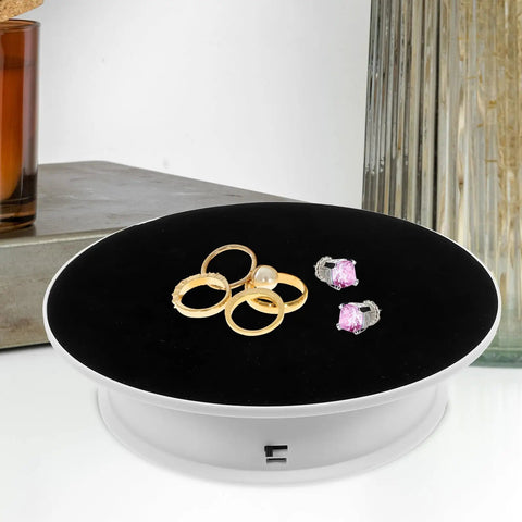 Ultimate 360 Degree Electric Turntable Rotating Display Stand With Two-Speed Adjustment For Jewelry Watches Photoshoot And Commercial Showcase Using White Base And Black Velvet Surface with rings displayed.