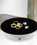 Stylish Electric Rotating Display Turntable For Jewelry Photography And Retail Store Use With Adjustable Speed Motorized Platform and Anti-Skid Base showing rings on black surface.