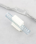 Close-up of a 60x22mm bi-fold closet door repair spring with metal coil and white plastic brackets on a gray background