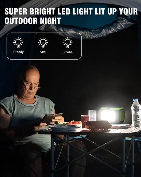 Man using smartphone with super bright LED light on camping table at night