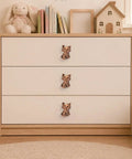 Hella Adorable 3D Sitting Cat Cabinet Knobs Four Pack Vintage Metal Drawer Pulls For Kitchen Cabinetry Upgrades With Embossed Fur Texture And A Super Chill Vibe To Liven Up Your House Today on a dresser with books and toys.