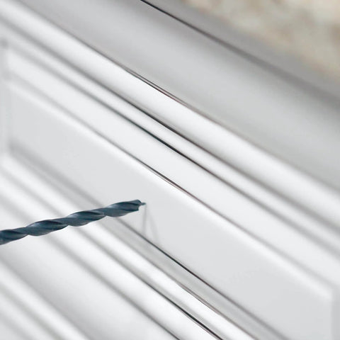 Close-up of DIY Friendly No-Fuss All In One Cabinet Door And Drawer Drill Mounting Template with drill bit on white cabinet door