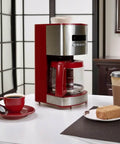 Front view of red 12 Cup Programmable Drip Coffee Maker With Auto Shut Off And Glass Carafe, Regular Or Bold Brews, on a table
